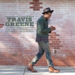 Gospel and Contemporary Christian Musician Travis Greene's Intentional song album cover depicting him walking on sidewalk beside a brick wall 