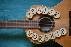 "Praise" and "Worship" etched in wood chips sitting on Covenant Award recipient's guitar - My Christian Musician