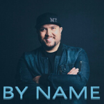 Micah Tyler poses with arms crossed as a cover art for his song, "By Name" - My Christian Musician