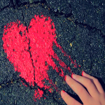 Hand touching a red, heart-shaped wet paint on an asphalt ground as a cover art for Micah Tyler's song, "Feels Like Music" - My Christian Musician